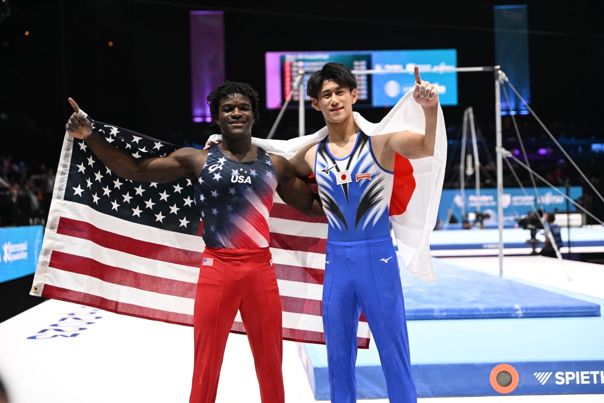 Fred Richard (left) and Hashimoto Daiki (right) raise their flag s after winning bronze and gold, respectivley, during the 2023 World Artisitc Gymnastics Championships.